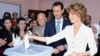A handout picture released by the official Facebook page of Syria's First Lady Asma al-Assad shows Syrian President Bashar al-Assad (C) watching on as his wife Asma casts her vote at a polling station in Maliki.