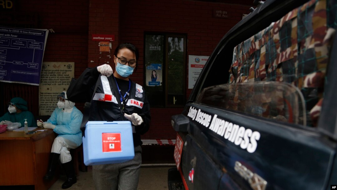 Punam Karmacharya, 22, of the RNA-16, Rescue and Awareness volunteer group, carries a box containing swab samples of patients to deliver it to a testing center, at a hospital in Bhaktapur, Nepal, May 26, 2020. 