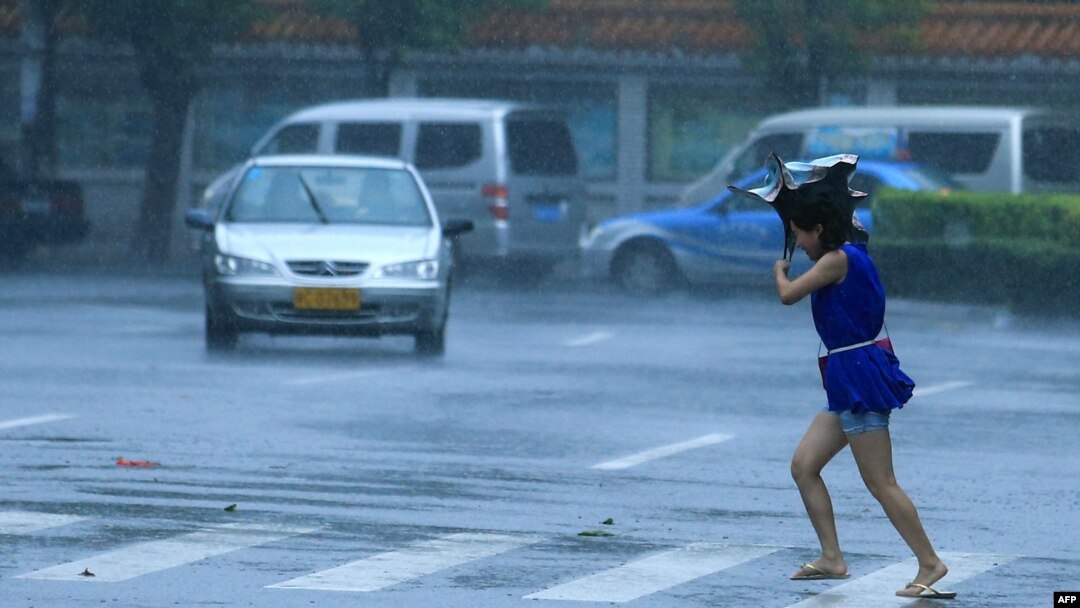 A woman walks on a street in heavy rain and strong wind in Haikou, south China's Hainan province, July 18, 2014.