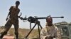 Somali government soldiers looking out from a machine gun mounted pick-up truck at Tobanka Buundo in the lower Shabelle region, near the Somalian capital Mogadishu, where residents created a road block during a protest against the Islamist Al-Shabab insur