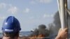 A cleanup worker watches a controlled burn near the Deepwater Horizon oil spill site.