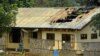 FILE - A woman stands outside the damaged roof of a school's dormitory, after it was set on fire, in Bafut, in the northwest English-speaking region of Cameroon, Nov. 15, 2017. 