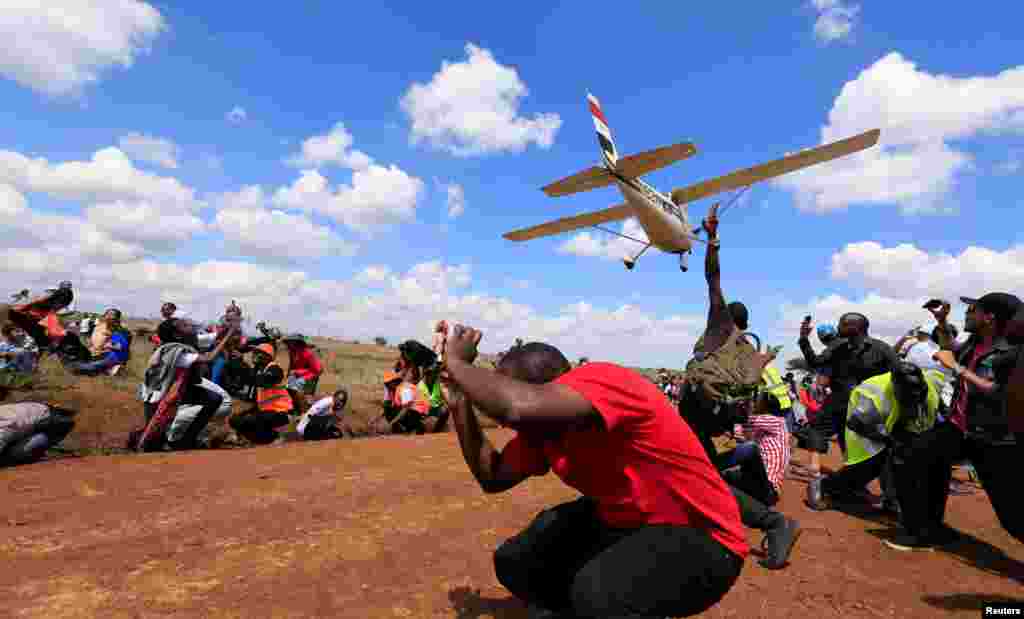 Spectators react as a plane flies over them during the Vintage Air Rally at the Nairobi national park in Kenya's capital Nairobi.