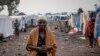 FILE - A woman walks at the Kayembe camp for dislaced persons, near Goma, Democratic Republic of Congo, Aug. 30, 2021.