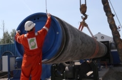 FILE - A worker puts a cap on a pipe at the construction site of the Nord Stream 2 gas pipeline, near the town of Kingisepp, Leningrad region, Russia, June 5, 2019.