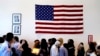 FILE - People file past the U.S. flag and a portrait of President Barack Obama on their way to attend a naturalization ceremony in Irving, Texas. 