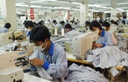 FILE - In this photo from 2007, workers sew shirts to be exported to the United States at Garment Co. 10 outside Hanoi, Vietnam. Today, Malaysia, Indonesia, Vietnam and other countries in the region are being forced to respond to the surging coronavirus caseloads with factory shutdowns and stricter lockdown and social distancing rules.
