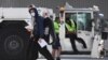 Tennis players and officials disembark from a flight after arriving in Melbourne on Jan. 14, 2021, to quarantine ahead of the Australian Open tennis tournament.