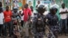 FILE - Ugandan riot police stand close to dejected opposition supporters to prevent them from demonstrating, shortly after the election result was announced, in downtown Kampala, Uganda, Feb. 20, 2016. 