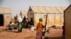 FILE - Displaced women prepare food at Kaya Camp, some 100 kms north of Ouagadougou, Burkina Faso, Feb. 8, 2021. The country's government is at loggerheads with a media outlet over claims displaced women have been forced into sex for food aid. 