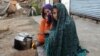 FILE - Internally displaced girls warm up by a stove after their family left their village in the Achin district of Afghanistan, due to clashes between the Islamic State group and other insurgent groups. 