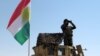 FILE - A member of the Kurdish security forces scans the horizon in Kirkuk, Iraq, from atop a military vehicle flying a flag of the Kurdistan Regional Government, June 14, 2014.