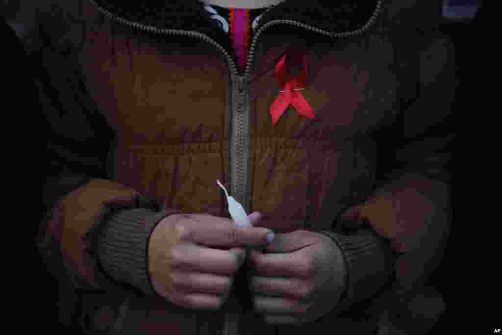 A Nepalese woman from "Maiti Nepal", a rehabilitation center for victims of sex trafficking, holds a candle before she lights it on the eve of World AIDS Day in Kathmandu, Nov. 30, 2016.