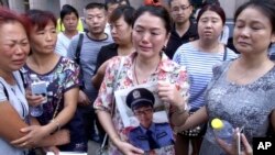 中国北部城市天津官员召开每日新闻发布会的宾馆外，一名女士拿着失踪的消防员儿子的照片。（2015年8月16日）