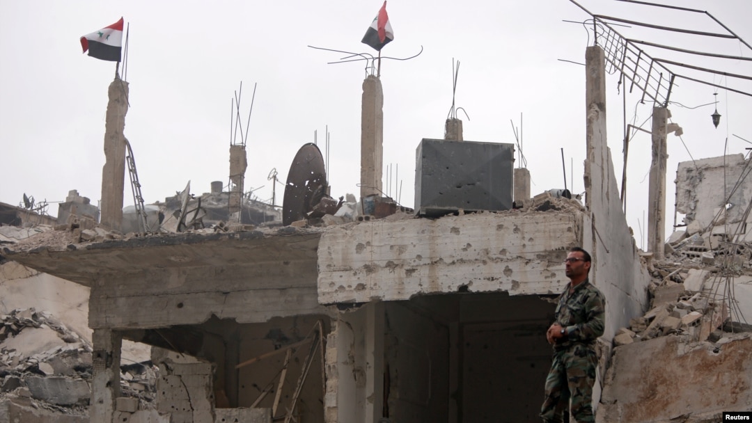 A Syrian army soldier stands at a damaged site in al-Hajar al-Aswad neigborhood, which was recaptured from Islamic State group militants on Monday. May 22, 2018.