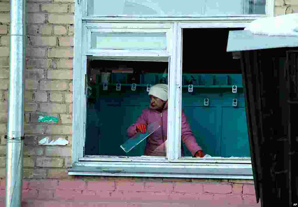 A woman cleans away glass debris from a window after the meteorite explosion, February 15, 2013.