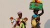 Hawkers walk past each other in the capital Luanda, Aug. 28, 2012. 