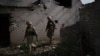FILE - Ukrainian government soldiers walk past a destroyed home near the line separating Ukrainian forces from Russia-backed separatist rebels, near Donetsk, Ukraine, May 4, 2021.