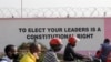 People pass by a painting on the wall of the Ugandan electoral commission compound in Kampala, Uganda, Jan. 13, 2021.