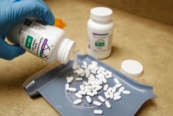 A pharmacy tech pours out pills of hydroxychloroquine at Rock Canyon Pharmacy in Provo, Utah, May 20, 2020.