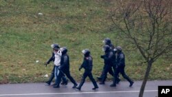图为在星期天的抗议中，白俄罗斯防暴警察逮捕了一名示威者。