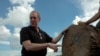FILE - U.S. Trade Representative Michael Froman looks at wood being inspected at a checkpoint designed to curb illegal logging in the region of Pucallpa, Peru, May 16, 2016.