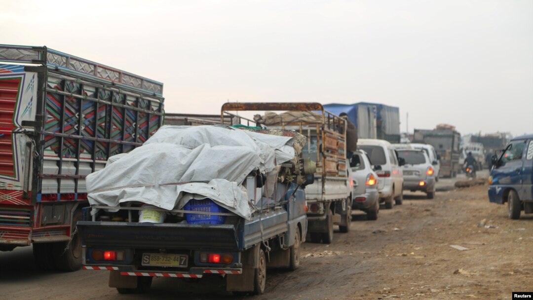 FILE - Trucks carry belongings of people fleeing from Maarat al-Numan, in Idlib province, Syria, Dec. 24, 2019.