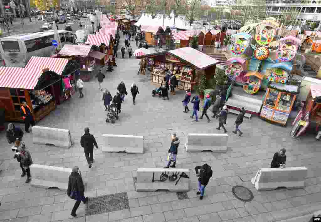 People walk past concrete barriers erected for the security of the Christmas market at Berlin&#39;s Breitscheidplatz square as the market opens to the public, Germany.