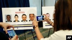Reporters photograph wanted posters of people facing criminal charges before a news conference in Washington, June 15, 2017, about the May 16, 2017 altercation outside the Turkish Embassy in Washington during the visit of the Turkish president. 