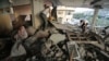 A Palestinian woman, left, cries inside her damaged house, which police said was targeted in an Israeli airstrike in Gaza City, July 17, 2014. 