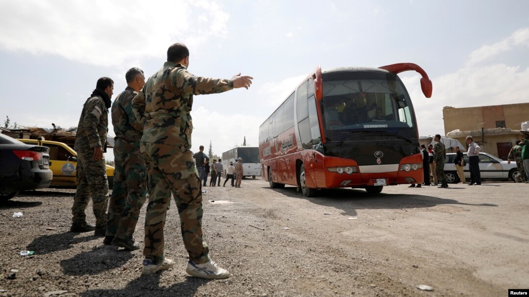 Syrian rebels and their families leave in a bus from a camp on the edge of Douma, April 9, 2018.
