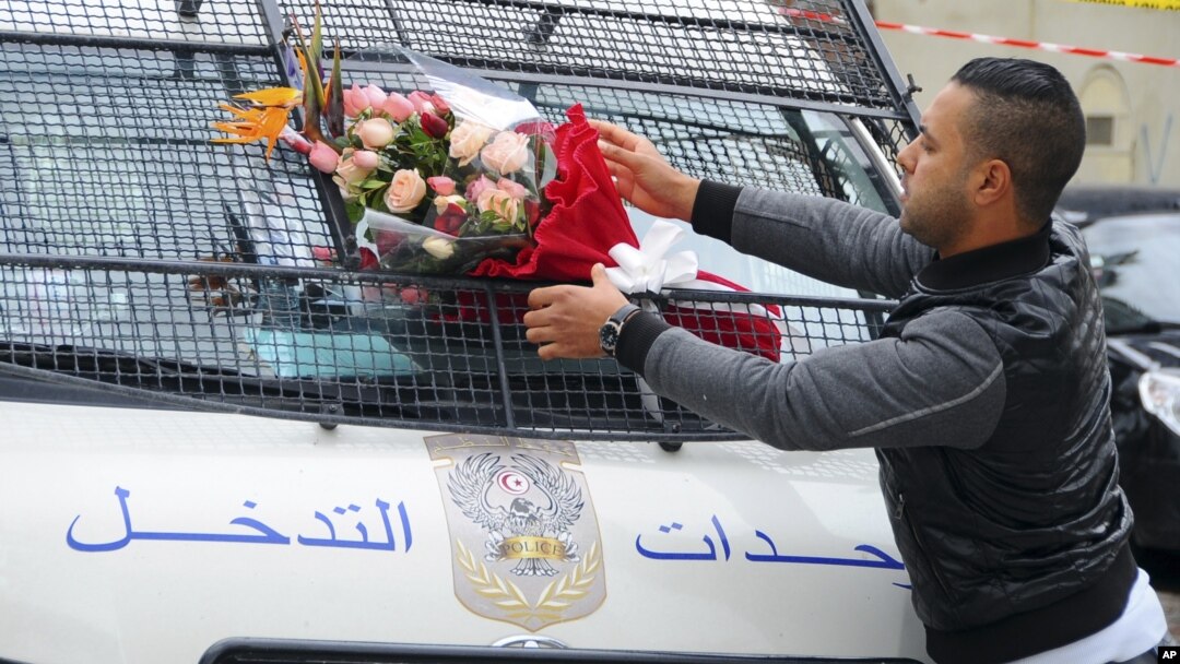 A man places a bouquet of flowers on a police van, near the bus that exploded in Tunis, Nov.25, 2015. 