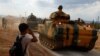 FILE - A boy salutes as Turkish Armed Forces vehicles drive pass by a village on the Turkish-Syrian border line in Reyhanli, Hatay province, Turkey, Oct. 11, 2017. 