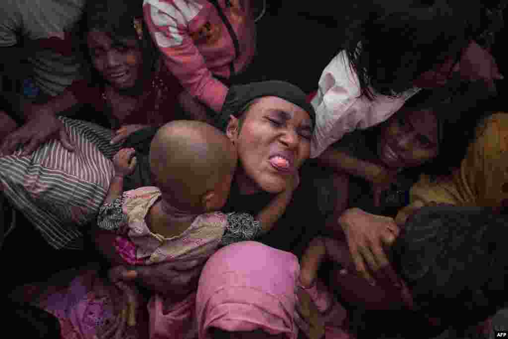 Rohingya Muslim refugees react as police and officials attempt to control a surging crowd as they wait to be called to receive food aid of rice, water, and cooking oil in a relief center at the Kutupalong refugee camp in Cox&#39;s Bazar, Bangladesh.