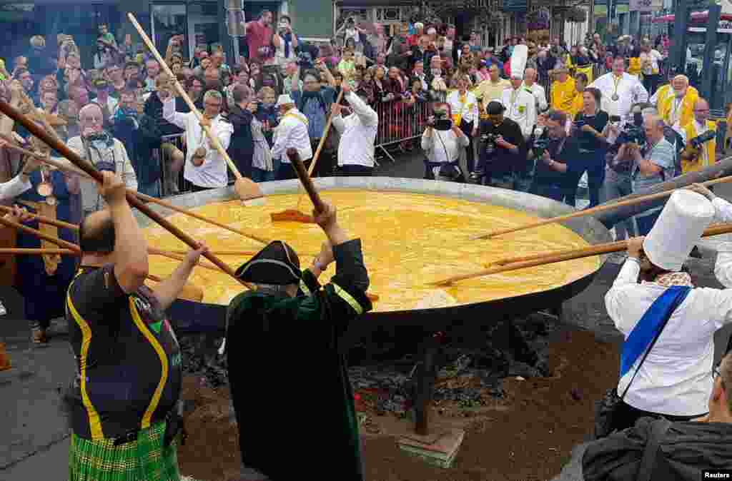 Members of the worldwide fraternity prepare a traditional giant omelette made with 10,000 eggs in Malmedy, Belgium.