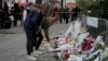 People lay flowers as part of a memorial to victims a day after more than 120 people were killed in a series of attacks in Paris, Nov. 14, 2015.