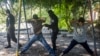 FILE - Two men are detained and searched by police in a park after a 911 call alerted police of possible gang members carrying assault rifles, in Ilopango, El Salvador, Aug. 31, 2015. 