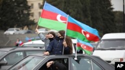 З національними прапорами азербайджанці святкували повернення своїх територій у Баку, 1 грудня 2020 року.  Тоді президент Азербайджану Ільхам Алієв назвав відновлення контролю над Лачинським районом та іншими територіями «історичним досягненням».
