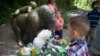 A boy brings flowers to put beside a statue of a gorilla outside the shuttered Gorilla World exhibit at the Cincinnati Zoo & Botanical Garden, May 30, 2016, in Cincinnati. 