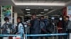 FILE - Passengers are asked to desinfect their hands upon arrival from international flights before being screened to detect signs of the coronavirus, at Entebbe Airport, in Entebbe, Uganda, March 3, 2020.