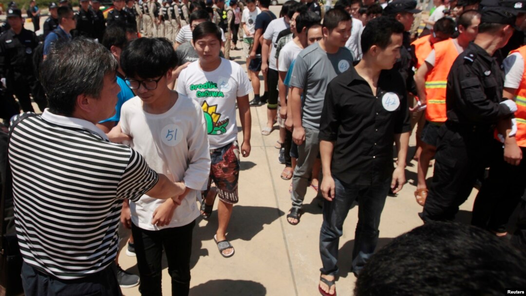 FILE - Chinese citizens who have been arrested over an alleged internet scam line up before a deporting back to China, at the international airport in Phnom Penh, Cambodia.