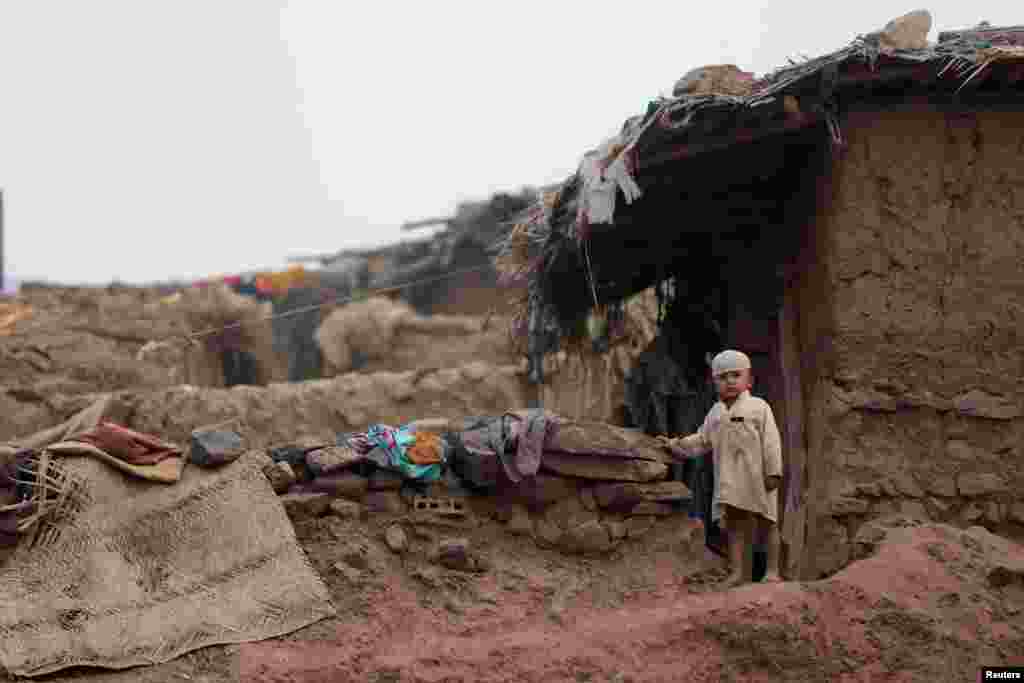 A boy stands beside his family home in an Afghan refugee camp in Islamabad, Pakistan.