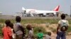 FILE - A humanitarian plane of the World Food Program (WFP) unloads sacks of cereal at Mpoko international airport in Bangui, which is located near a camp for displaced people.