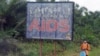 FILE - A man stands next to an AIDS billboard as he cleans a street in Yaounde, March 20, 2009. 