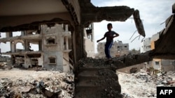 G'azoda Isroil hujumidan vayron bo'lgan uylardan birini yosh falastinlik bola ko'zdan kechirmoqda, 11-may 2015-yil.