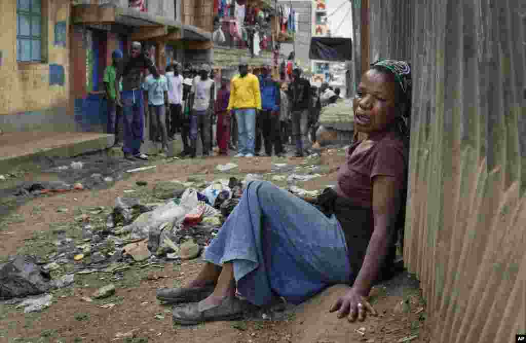 A relative wails on the floor of an alleyway near the body of a man who had been shot in the head as the angry crowd shouts at the police, in the Mathare slum of Nairobi, Kenya. Kenya's election took an ominous turn as violent protests erupted in the capital.